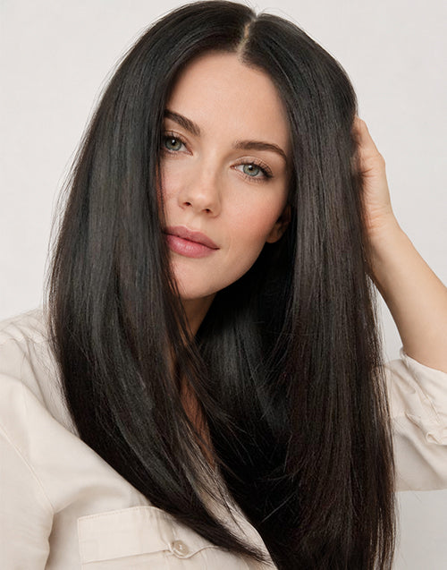 A woman with long, straight, black hair posing against a light gray background.