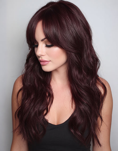 Three-quarter shot of a woman wearing a dark red burgundy human hair wig with soft face-framing curtain bangs and natural wavy texture.