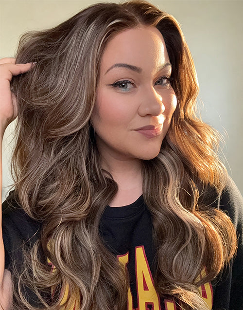 Woman wearing long wavy lace front wig with honey blonde balayage highlights and dark shadow roots, naturally blended styled waves.