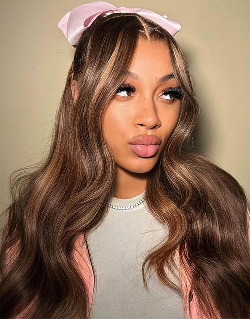 Real model styled look wearing Jessie's Wig long highlight wavy human hair lace front wig in a half-up half-down hairstyle with a pink bow accent.