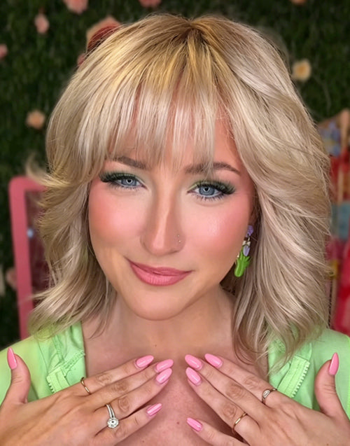 Close-up portrait of a woman with a dimensional medium blonde shag haircut, wispy bangs.