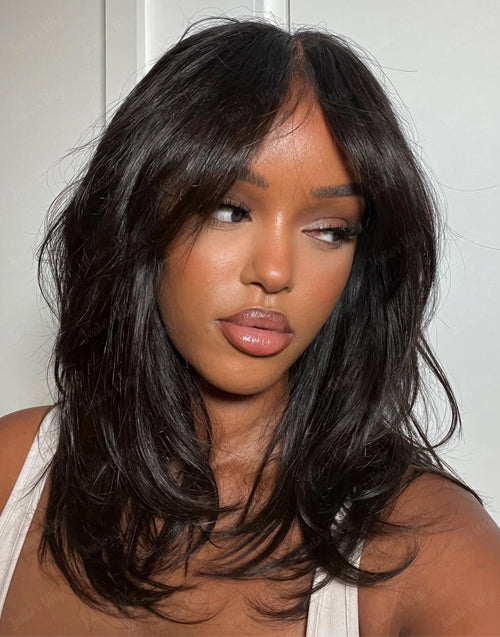 Angled model selfie wearing the pre-cut 5x6 lace glueless human hair wig with wavy layered cut and natural curtain bangs.
